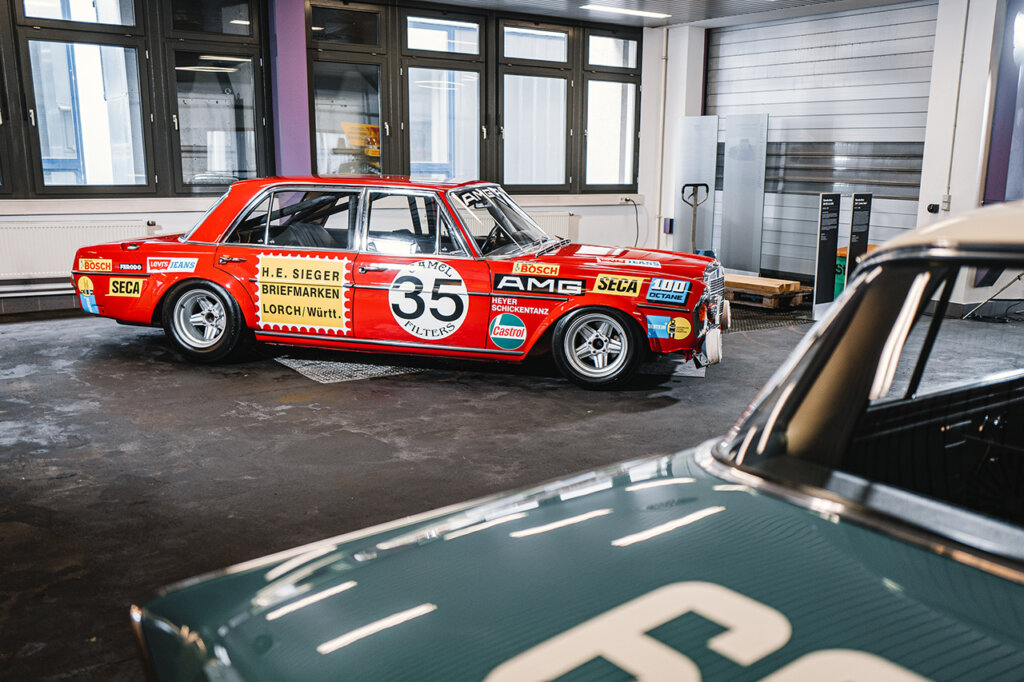 Red SEL300 with decals all over it in a garage next to a green car