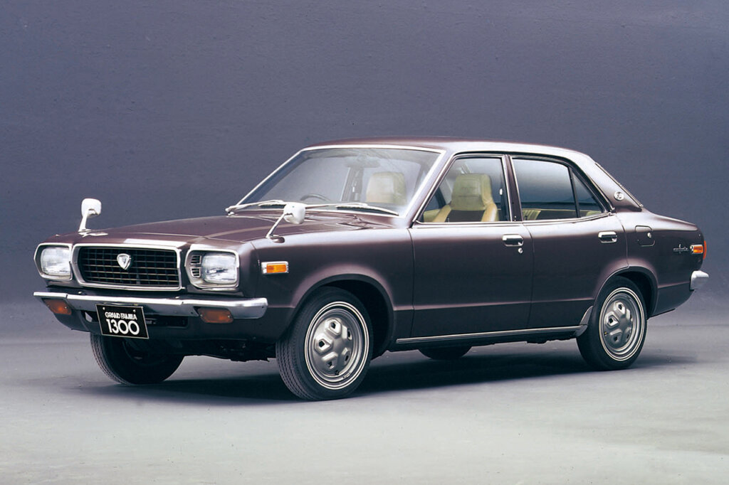 brown Mazda grand familia parked in a room with a solid color background behind it