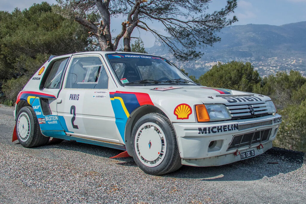 White with accent colors of a Peugeot T16 parked near grass and trees