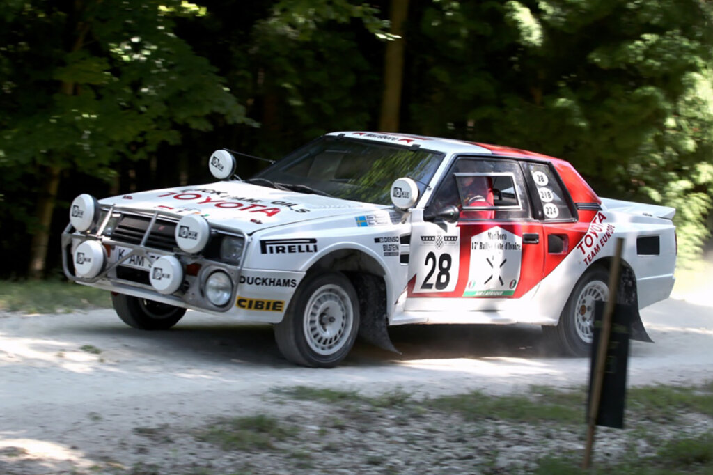 White and red Toyota driven by a man passing trees