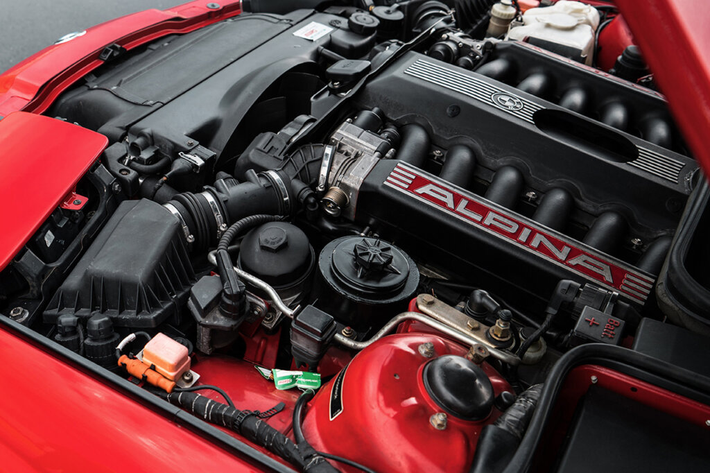 red 7-series BMW Alpina with a black valve cover with the word Alpina on it