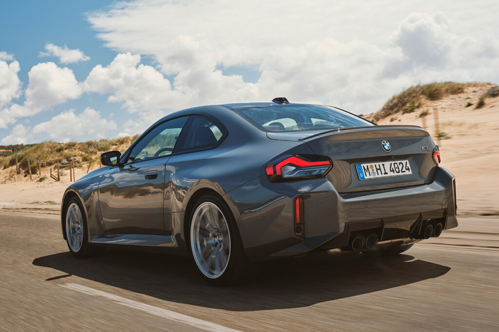 grey M2 driving with cloudy blue sky in background