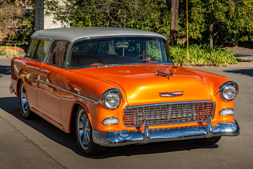 Orange and white Chevy Nomad with chrome accents shot with trees in background