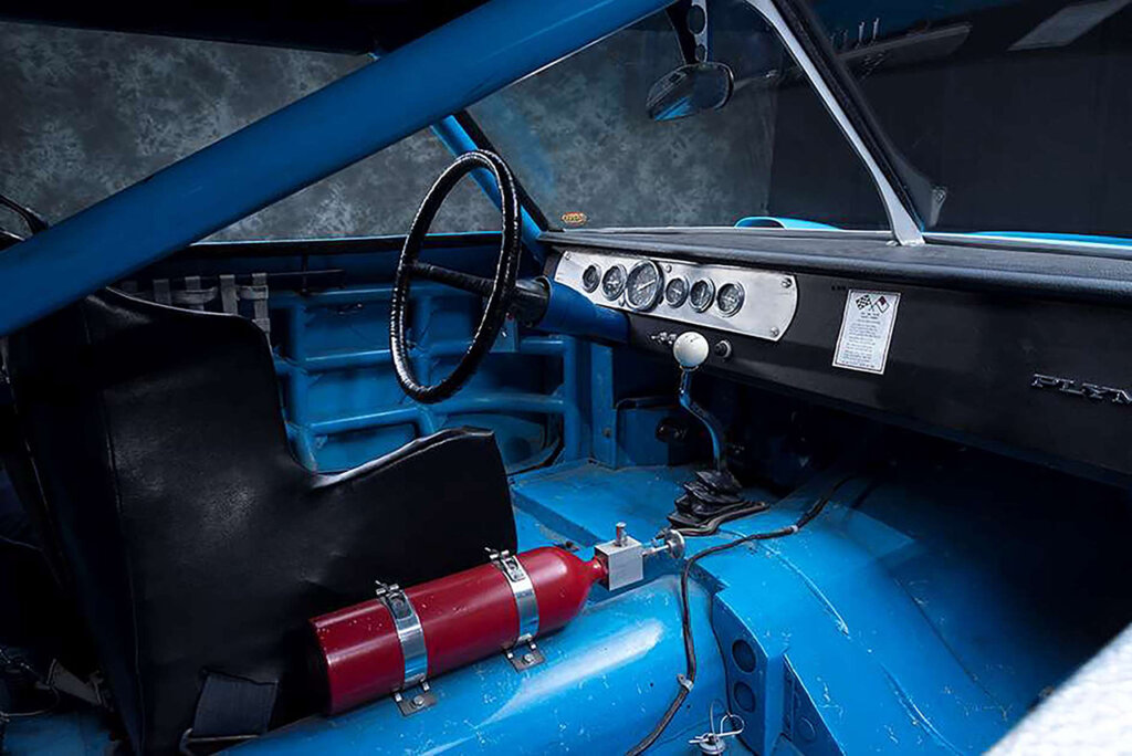 Black seat next to a fire extinguisher with bare metal exposed in a blue car