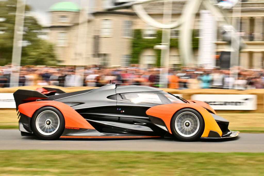 Black and orange supercar passing spectators at Goodwood 2024