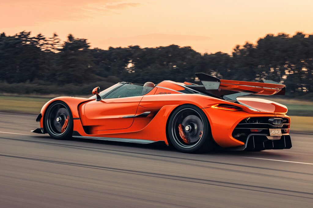 Man driving an Orange Koenigsegg Jesko Attack with the sun set in background