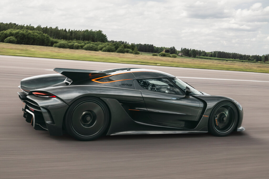 black Jesko Absolut driving fast on a racetrack with grass and trees in background