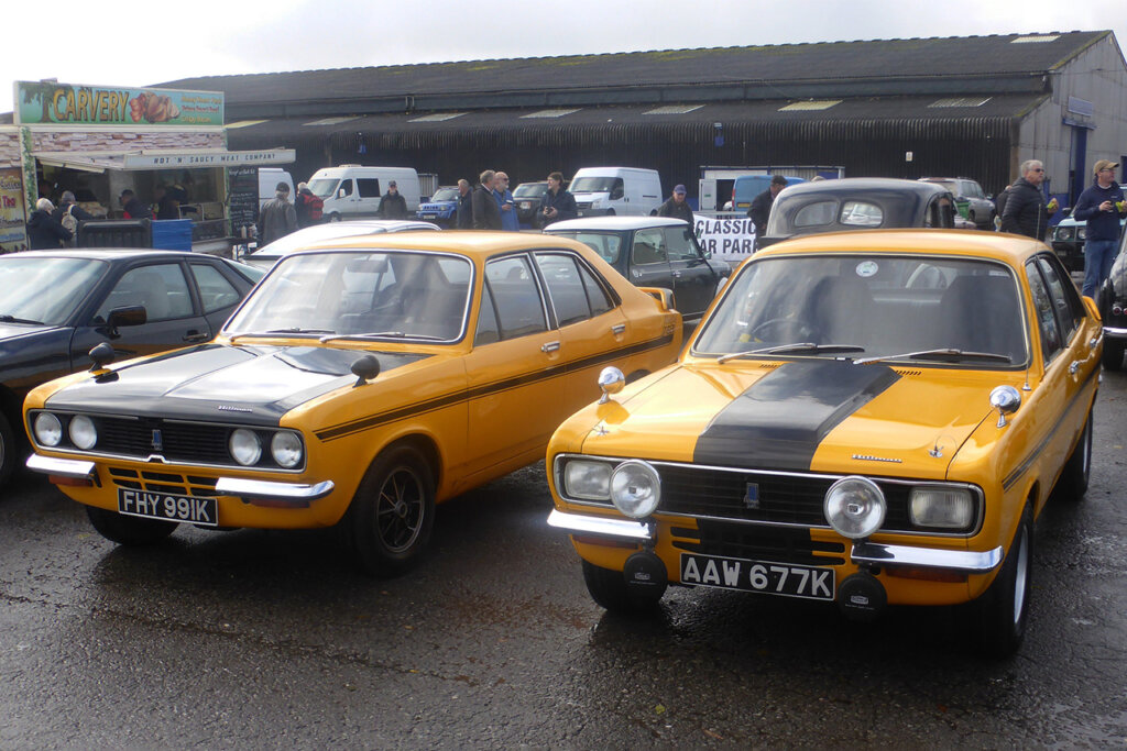 Two yellow and black cars parked near many other cars in a lot