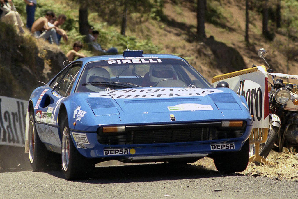 Blue Ferrari 308 with rally racing spectators in background