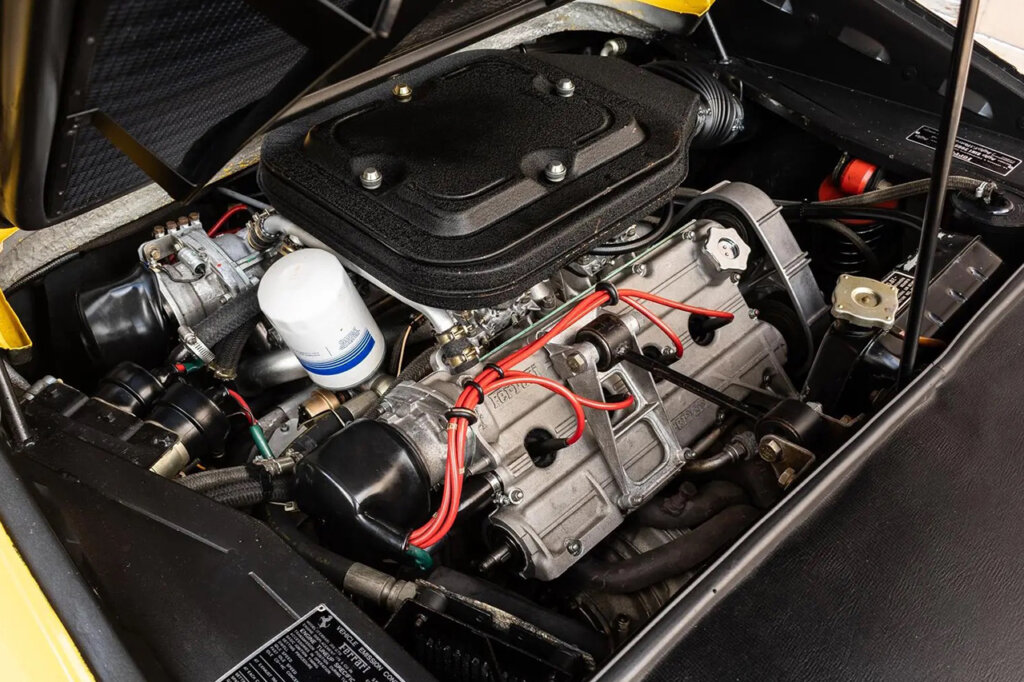 Engine bay of a Ferrari 308 vehicle with a black plastic valve cover