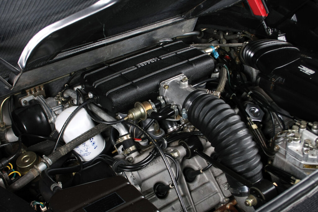 black engine bay with an engine covered by a black valve cover and a white filter