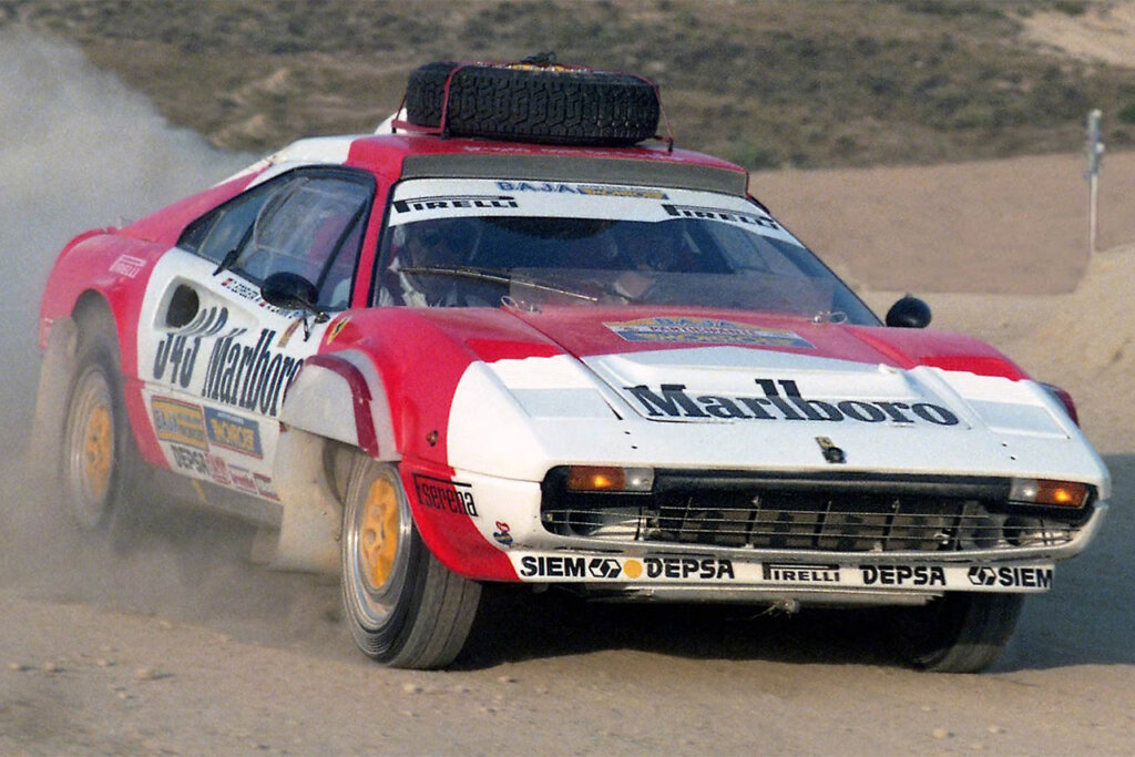 Red and white Marlboro group B rally race car with a spare tire on the roof driving fast