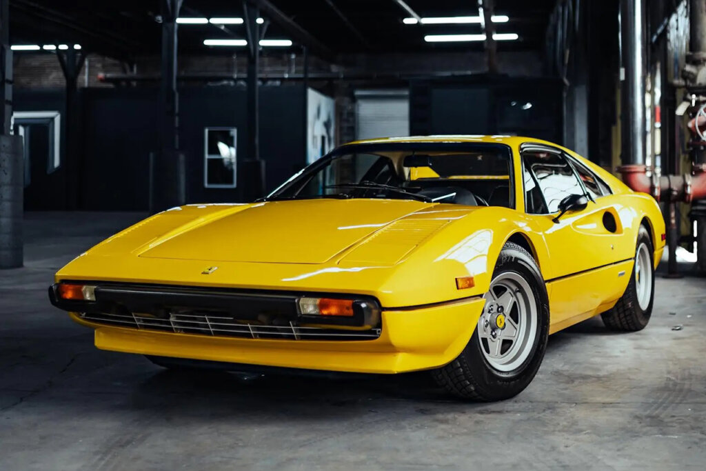 Yellow Ferrari 308 parked in a warehouse with dimly lit lights