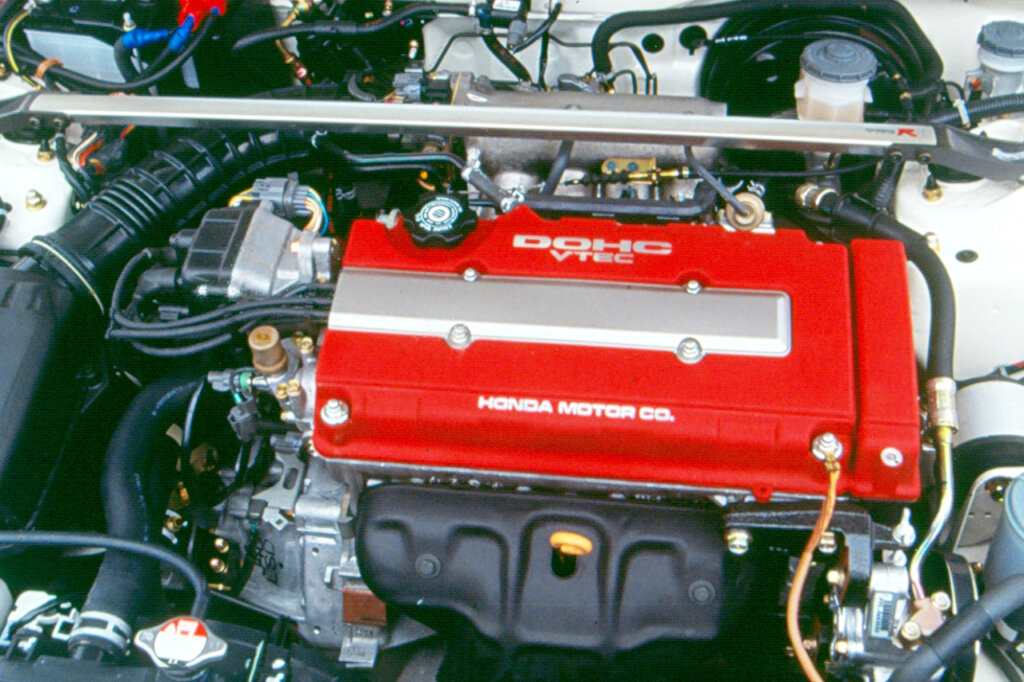 Red valve cover of a Honda engine inside of a white car
