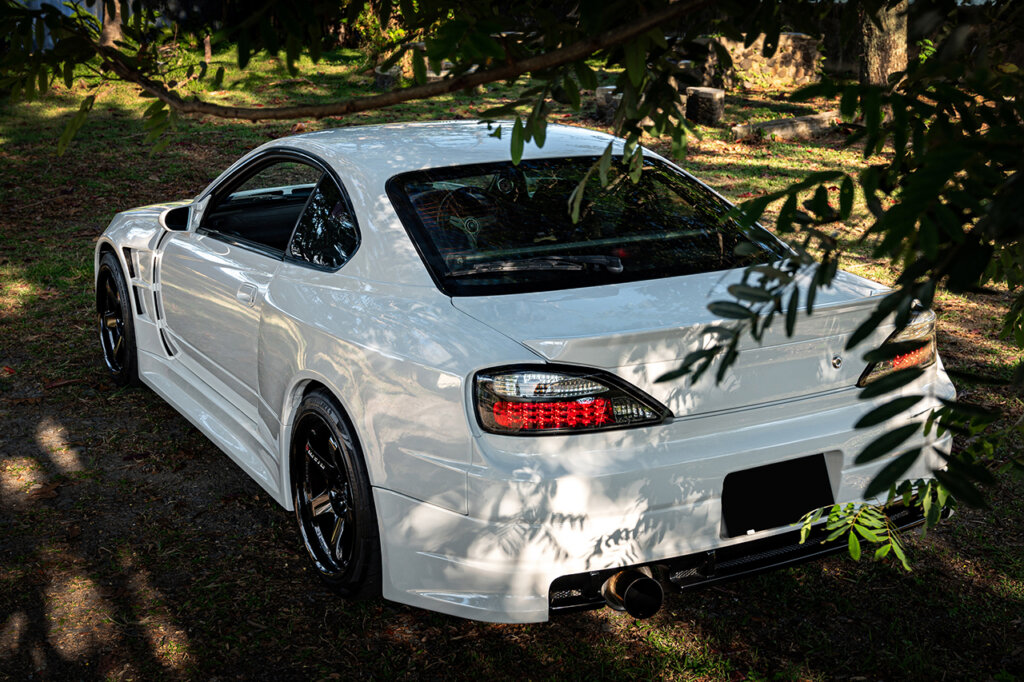 White Nissan S15 parked under trees hanging over the car