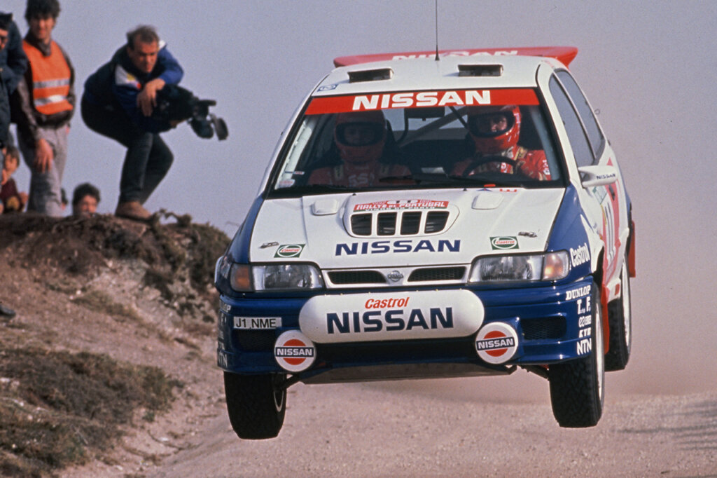 Blue white and Red Nissan in the air passing spectators closely