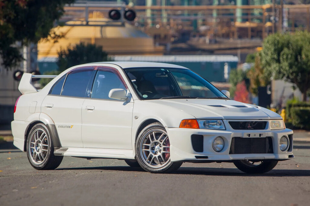 White Evo 5 parked at an angle with rail road lights in the background