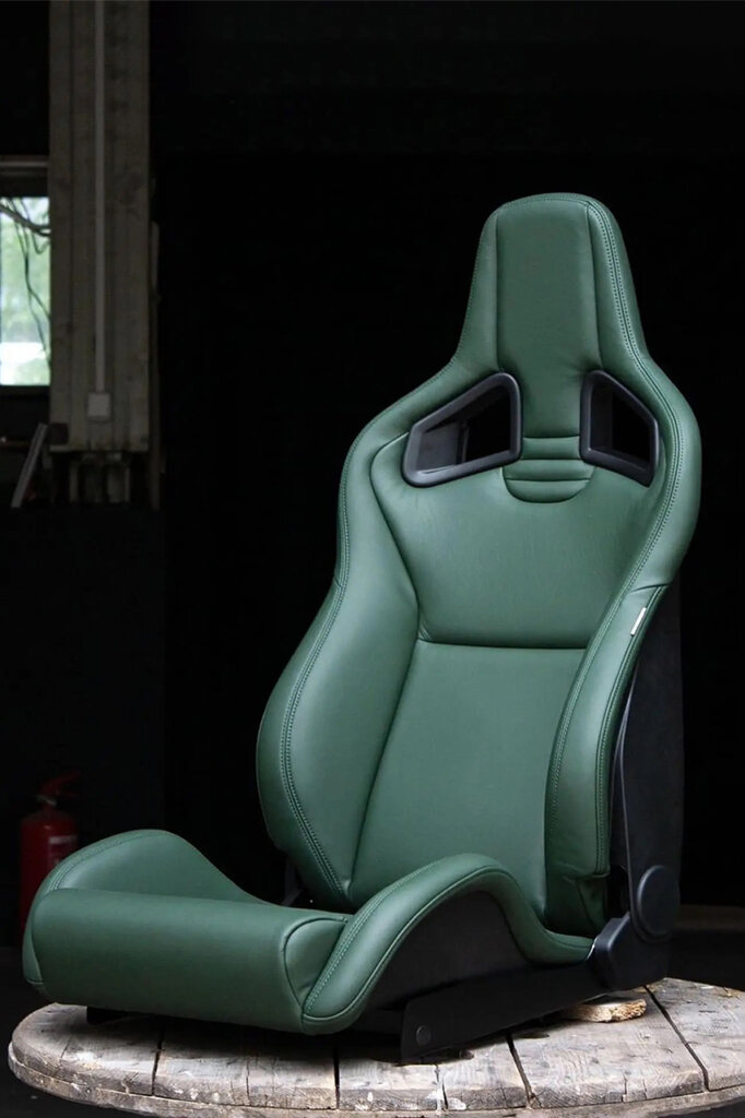 Green leather seat with two large openings towards the top placed on a wooden table and dark background
