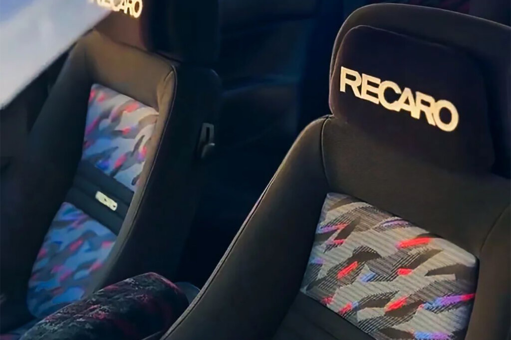 Closeup of two seats with confetti style pattern with large white Recaro branding on the headrest