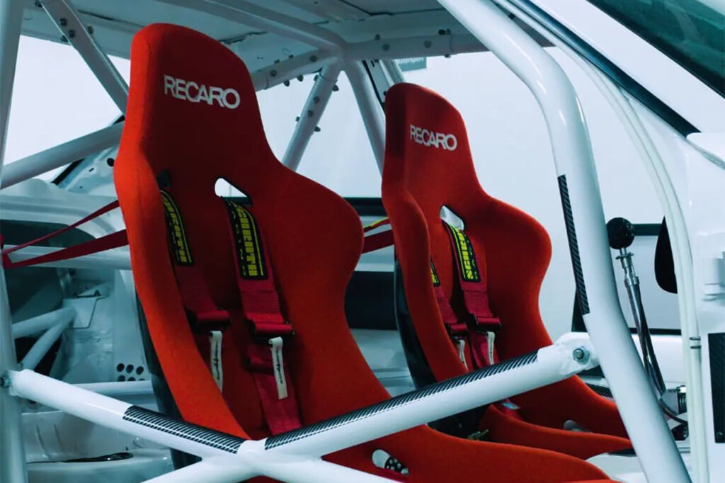 red recaro seats with white lettering in a white car with tubing surrounding the interior