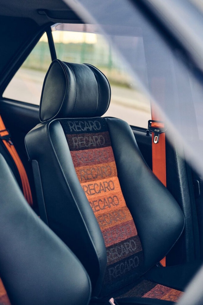 orange and black leather seat with the word Recaro repeating in the center of the seat