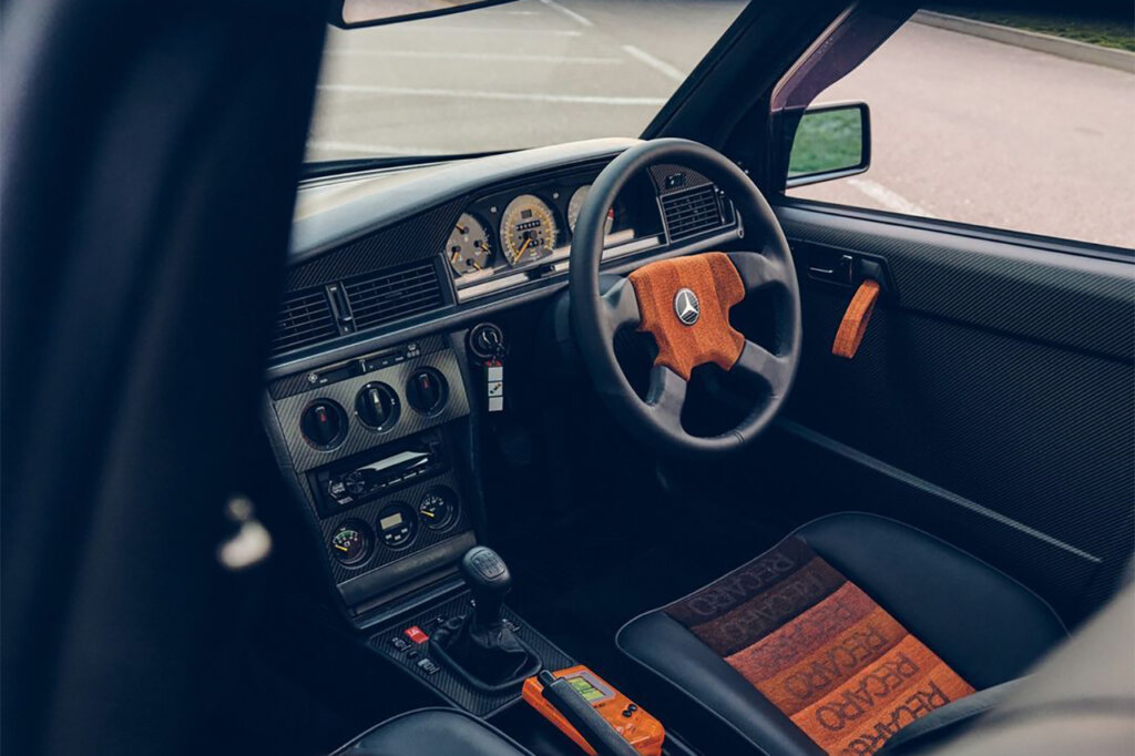 Black leather and orange Recaro seats in side of a Mercedes vehicle