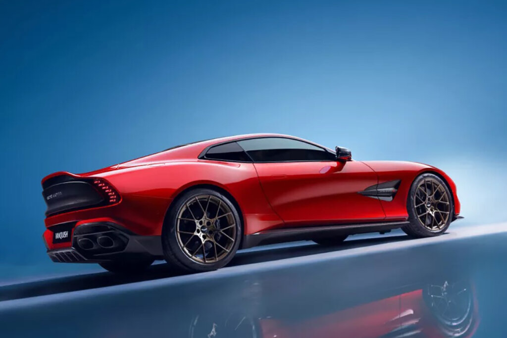 Red Aston Martin Vanquish with bronze wheels parked in a structure with blue background