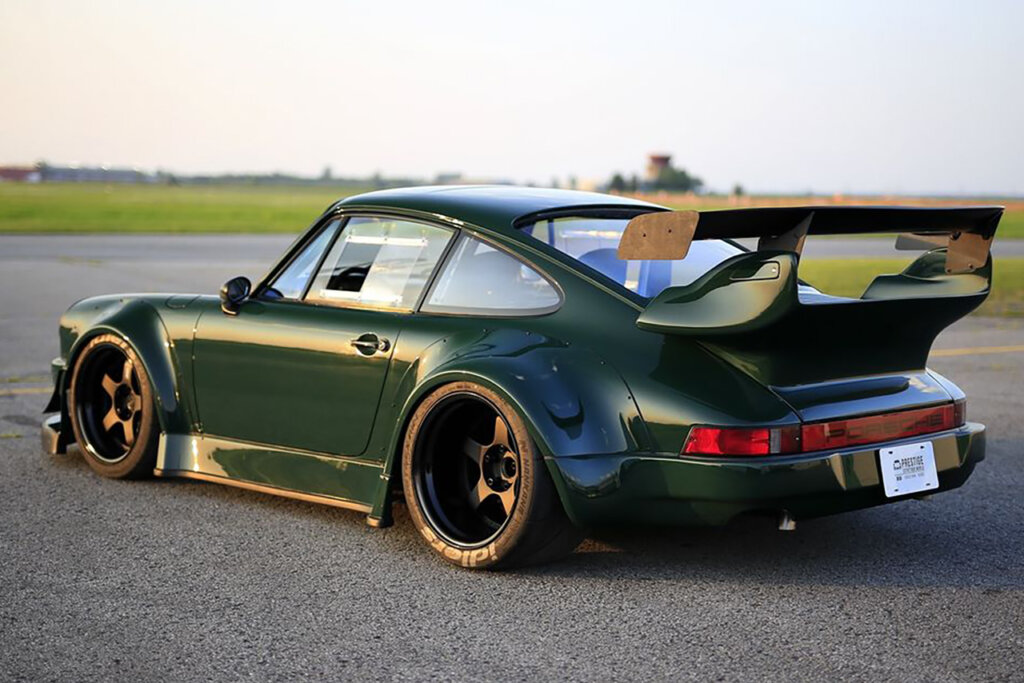 Green RWB Porsche 911 parked with some grassy fields behind the car