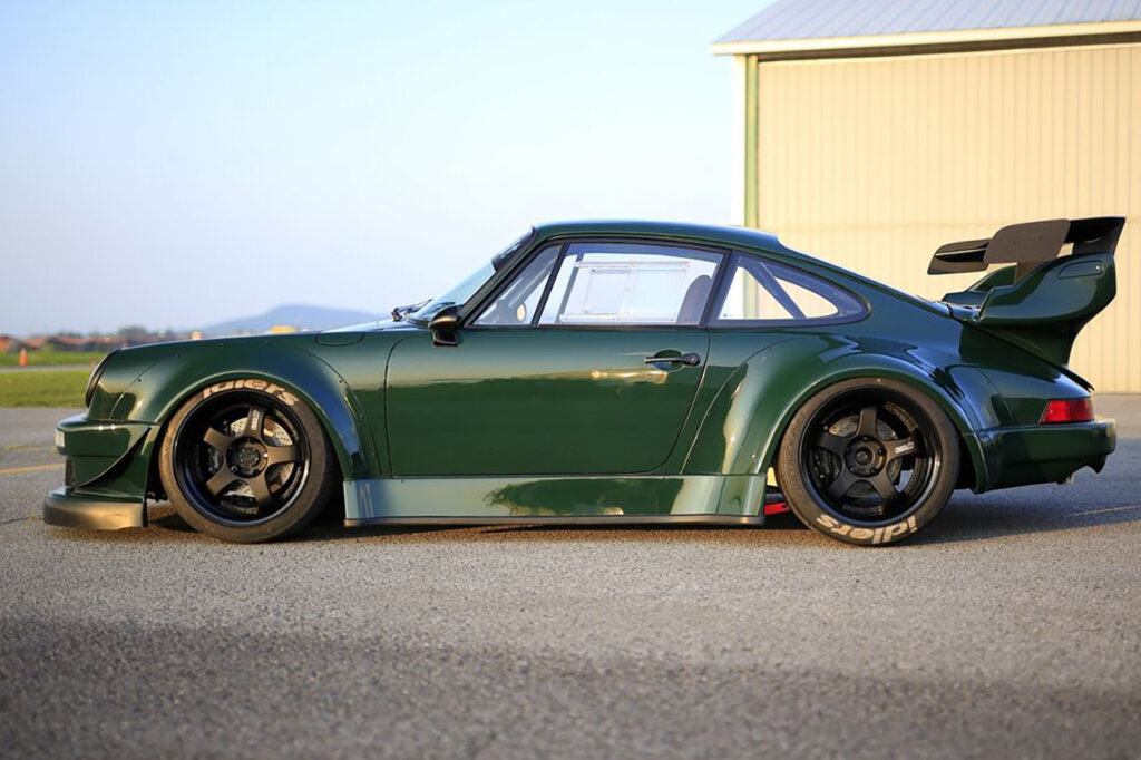 Green RWB Porsche with a beige building in the background