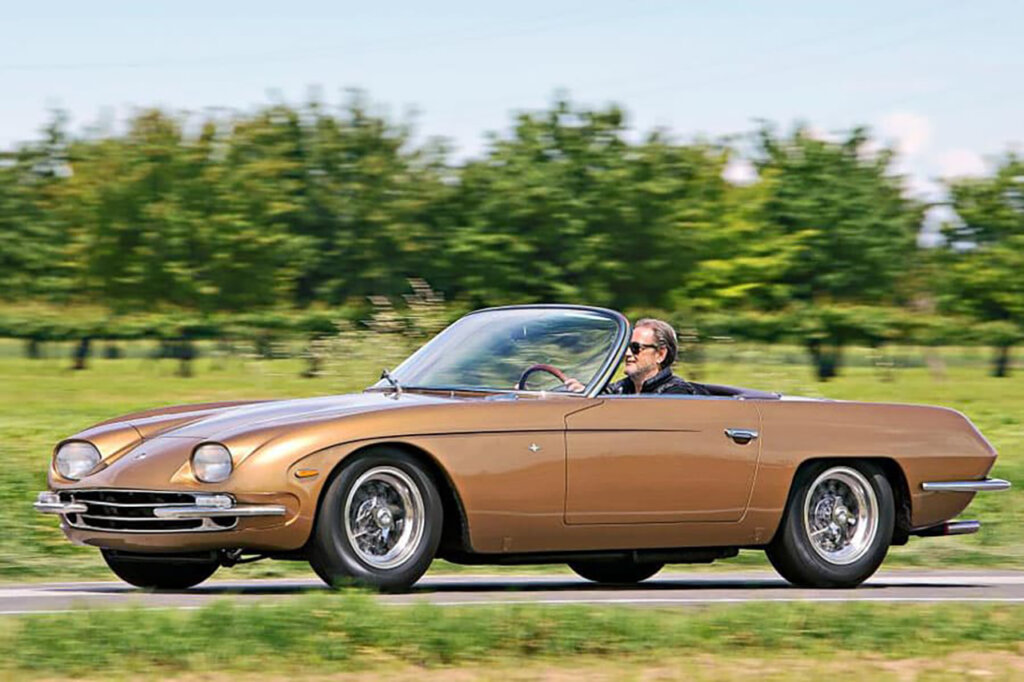 Brown Lamborghini 350 GTS driven by a man on a road passing grass fields