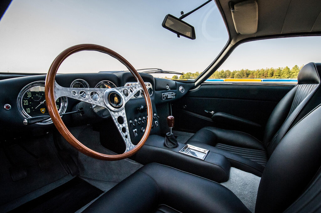 Black leather interior with brown wood grain steering wheel with the Lamborghini logo on the horn