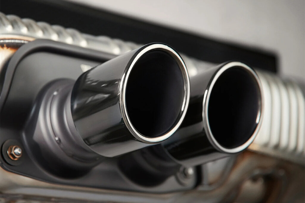 Two exhaust tips with metal ridges on the panel behind these