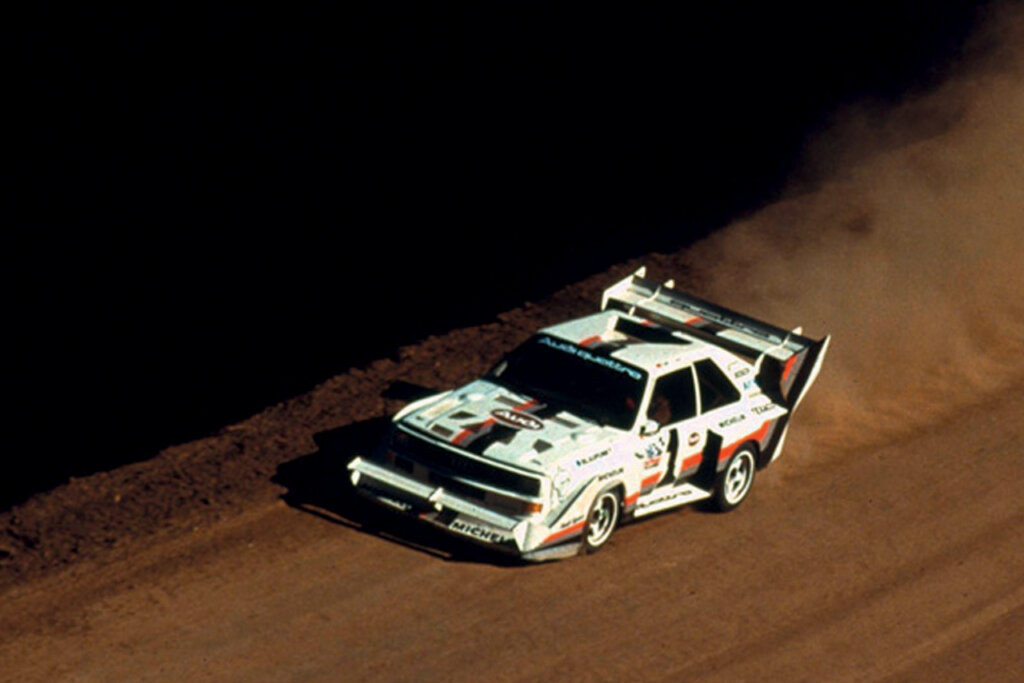 White Audi S1 E2 driving on the dirt leaving a cloud of smoke behind it