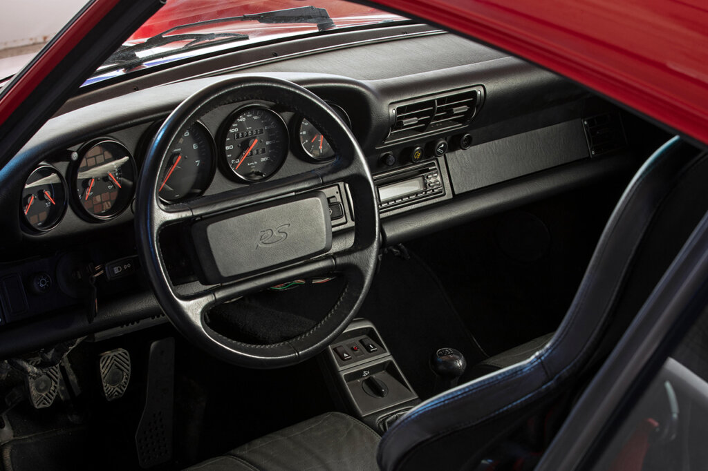 Black interior with a stamped RS logo on the steering wheel of a red Porsche 911 964