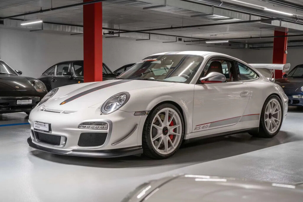White 997 GT3 RS parked in a showroom garage with several cars surrounding the car in the background