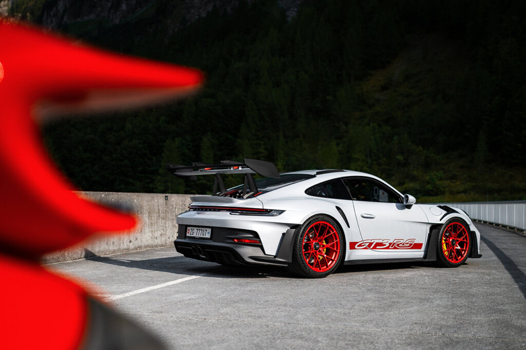 White with red accents of a 911 992 GT3 RS parked on a bridge with a red 911 out of focus parked infront of the car