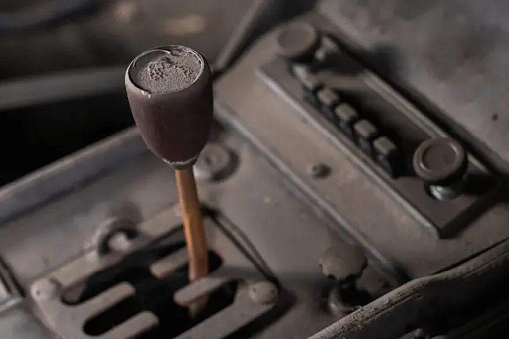 dust covered center console with a gated shift transmission and a brown shifter of a car