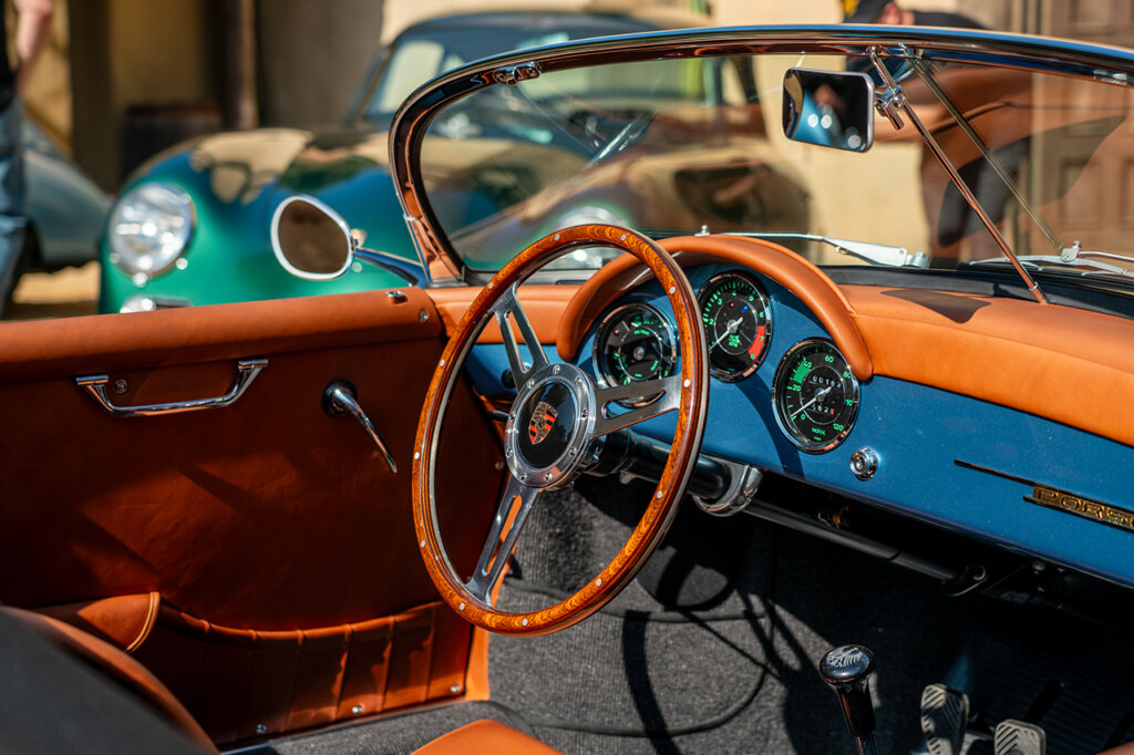 brown wood grain steering wheel in side of a blue Porsche with orange leather door cards