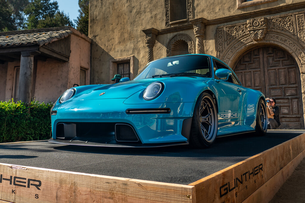 light blue Guntherwerks 911 993 propped up on a wooden stage with black carpet in front of a wood paneled door