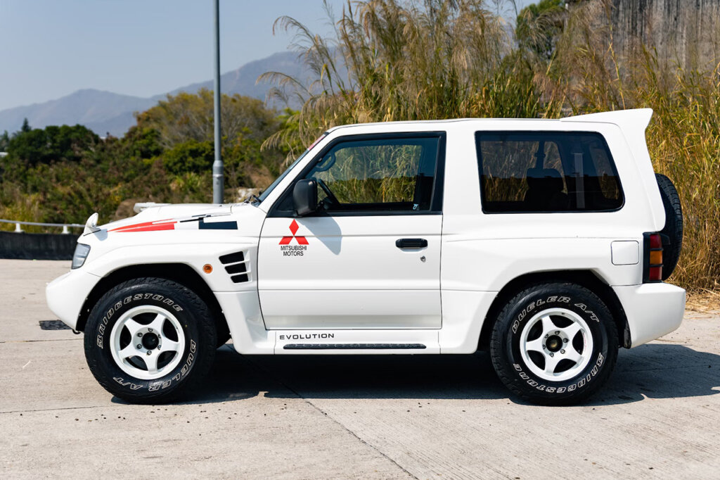 White Pajero SUV parked in a driveway with trees in the background