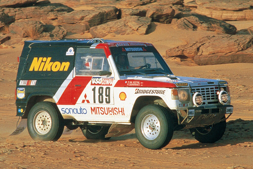 Green, red and white Mitsubishi Pejaro parked on dirt