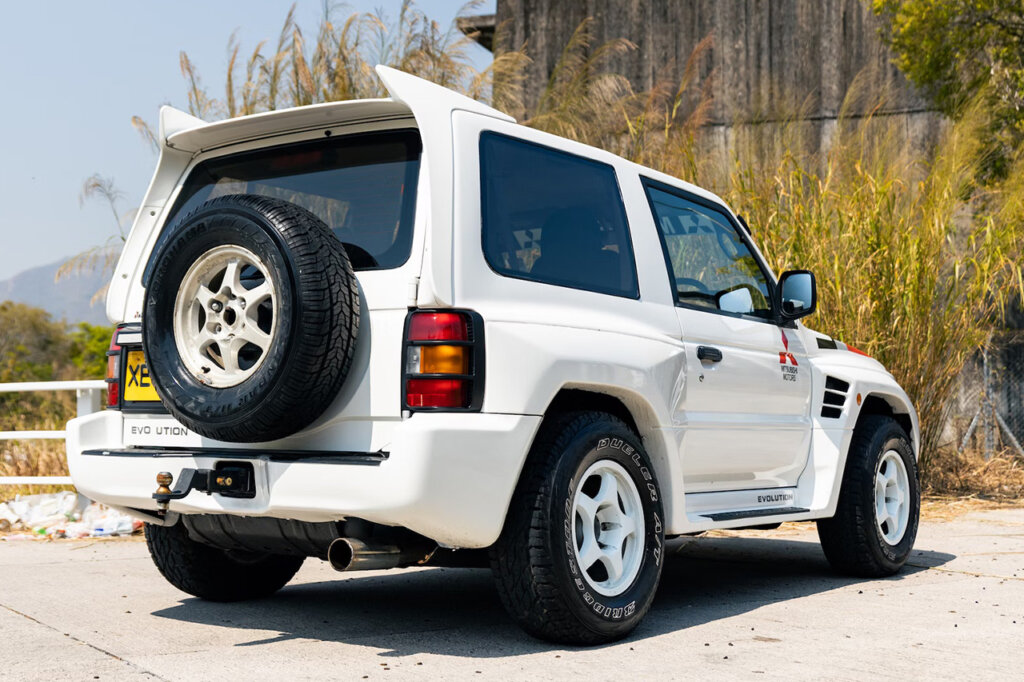 White Mitsubishi Pajero parked facing some shrubs in the background