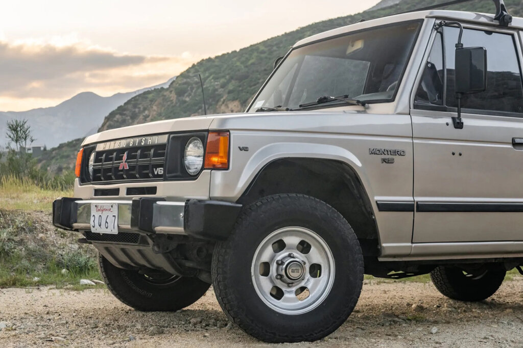 Mitsubishi Pajero with sun setting in the background with green mountains