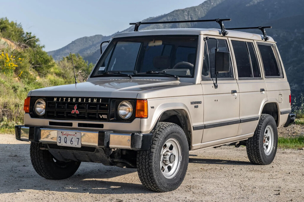 Grey Mitsubishi Pajero parked with mountains in the background