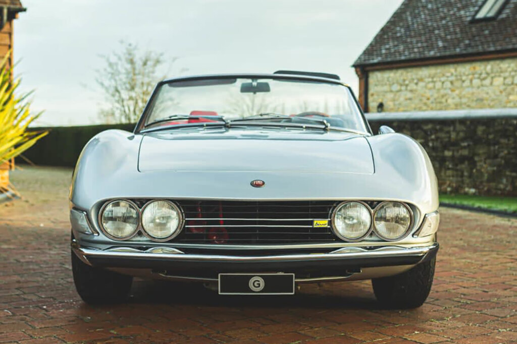 Silver Fiat Dino parked in a brown brick driveway
