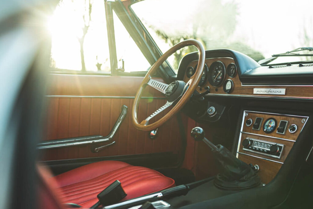 Red leather interior seats with wood grain accents inside of a silver Fiat