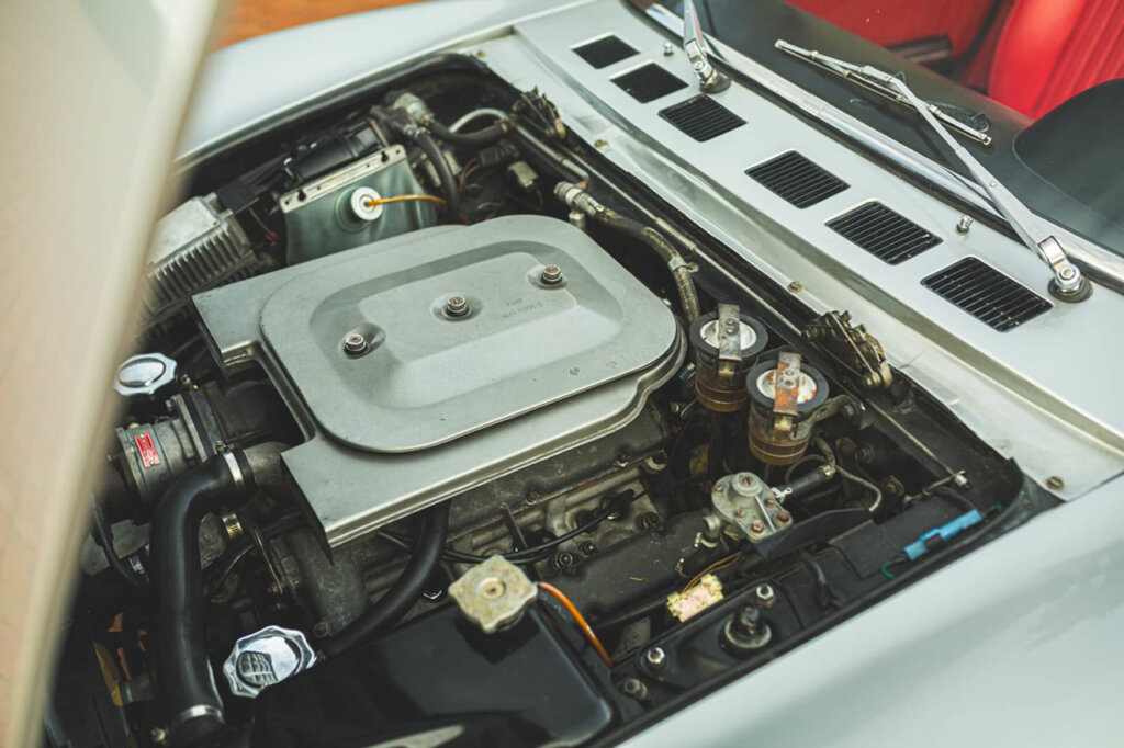 Silver grey engine cover with black engine parts inside of a silver Fiat