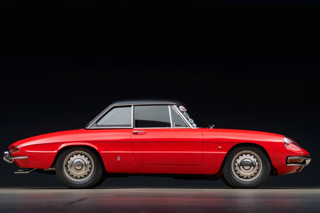 Red with black roof Alfa Romeo Duetto shot in a showroom with a black background