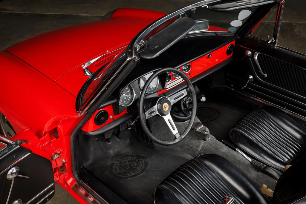 Black leather interior with a modified steering wheel with a red dashboard going from left to right