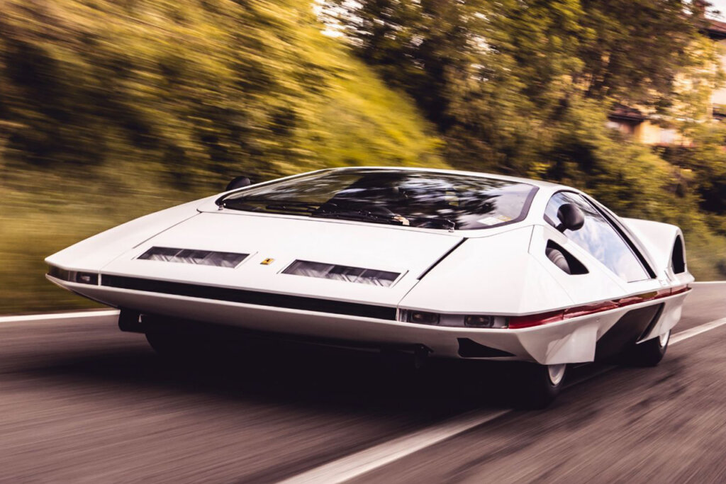White Ferrari 512S Modulo driving fast on a road passing trees